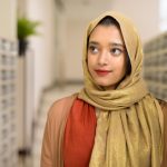 Portrait of young beautiful Indian Muslim woman with hijab at the mailbox of modern building